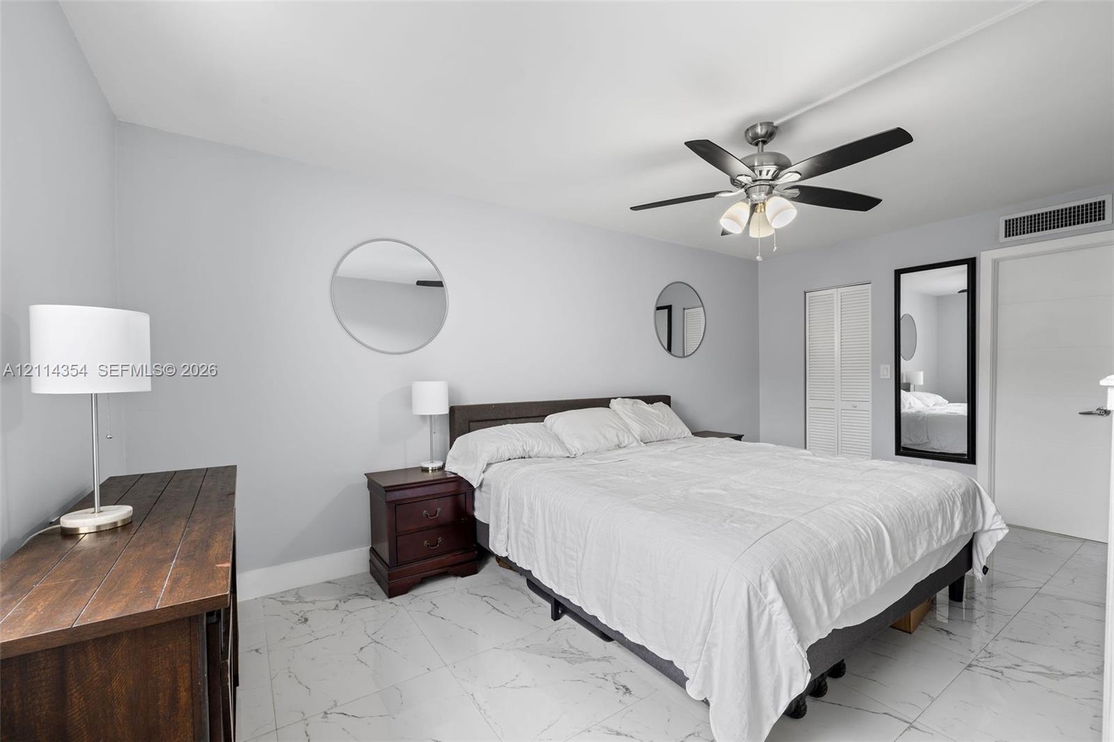 Neutral-toned interior featuring large-format tile flooring, a multi-blade ceiling fan with integrated lighting, and a bi-fold closet door