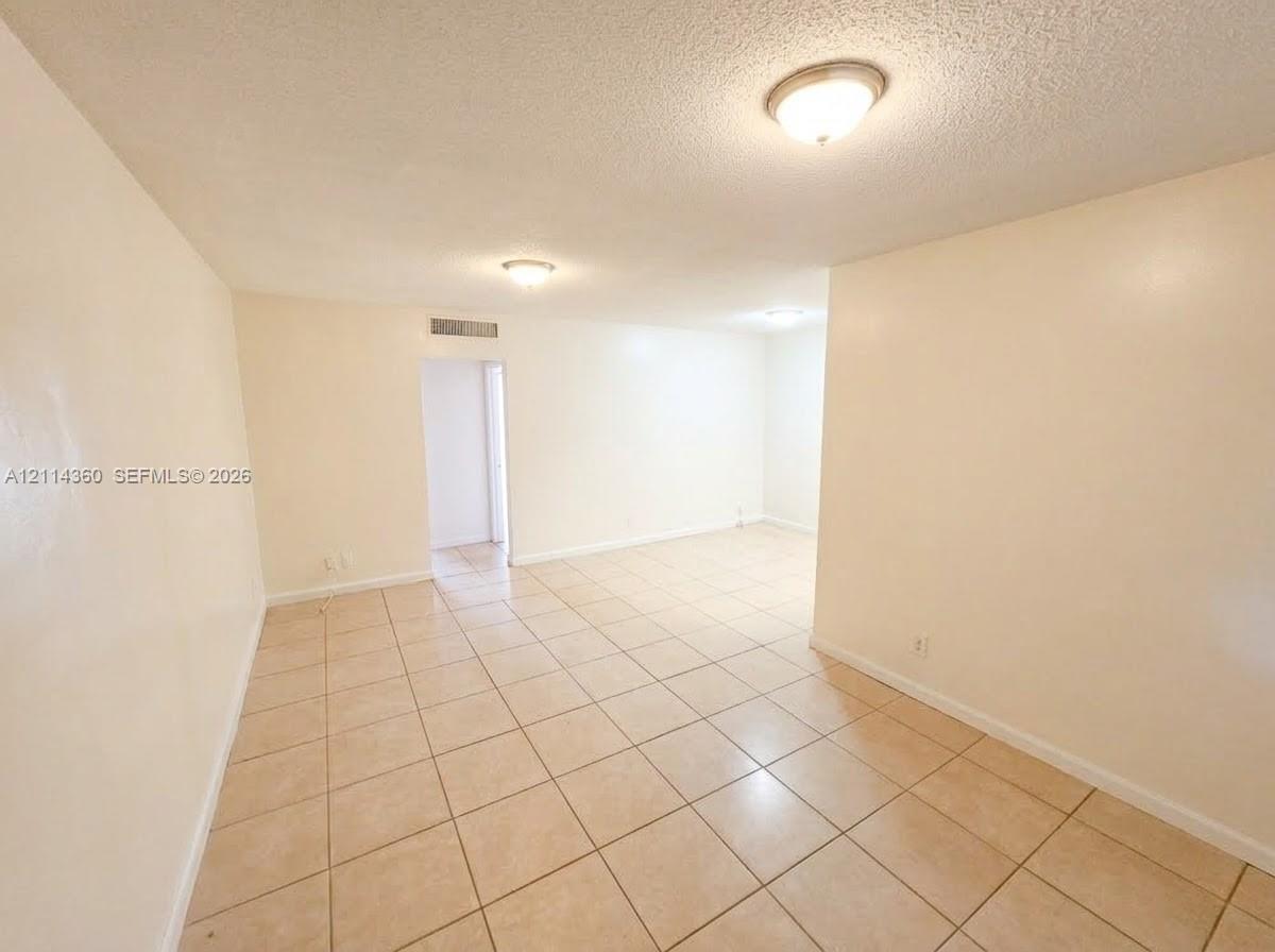 Neutral-toned ceramic tile flooring, textured ceilings, and flush-mount lighting fixtures Neutral-toned ceramic tile flooring, textured ceilings, and flush-mount lighting fixtures