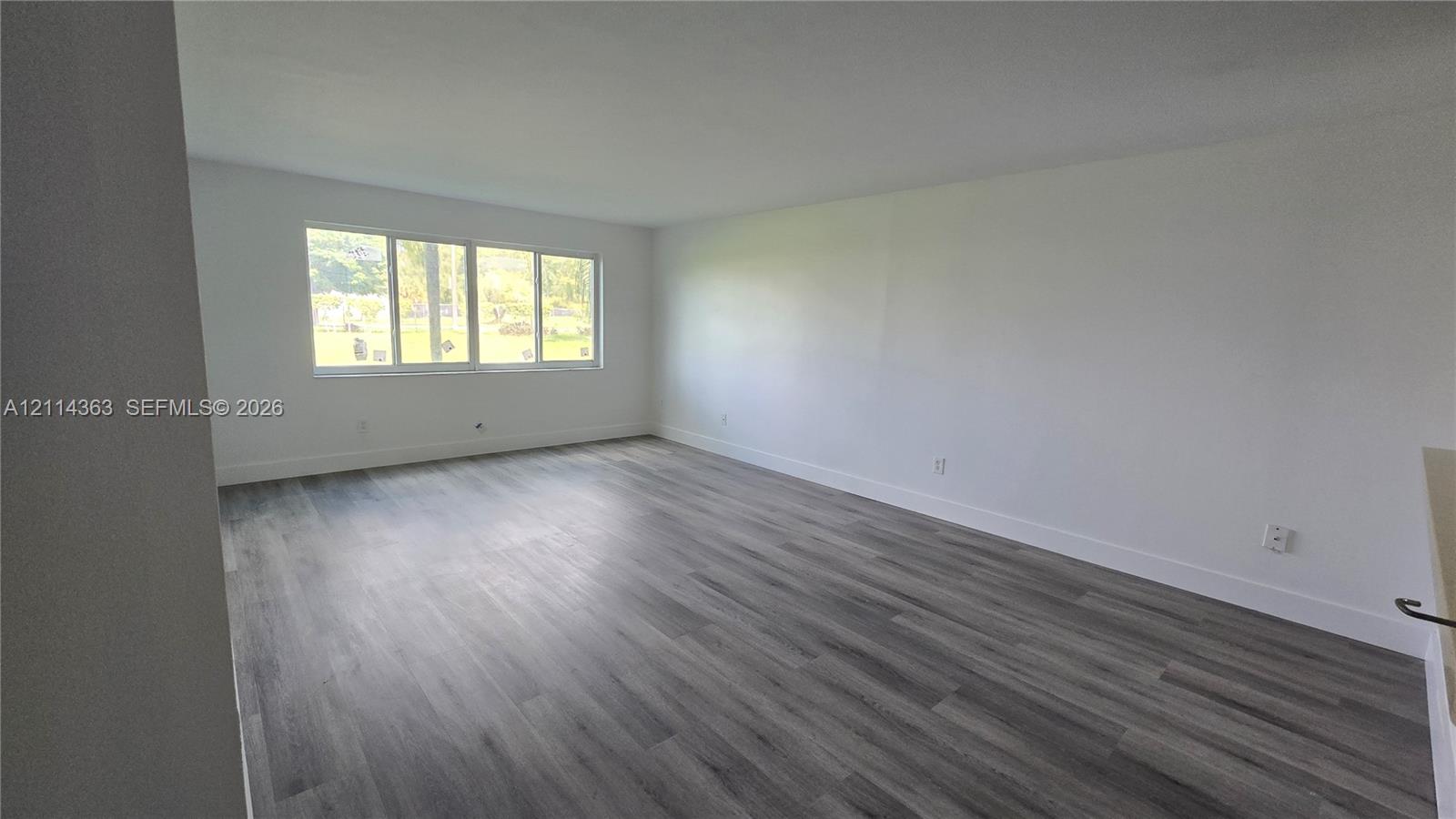 Neutral interior featuring wood-finish flooring and a multi-pane window
