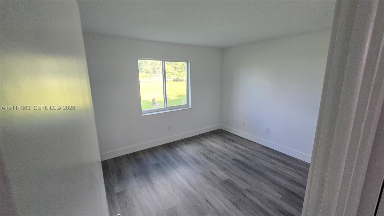 Interior space featuring wood-finish flooring, white walls, and a single-pane sliding window
