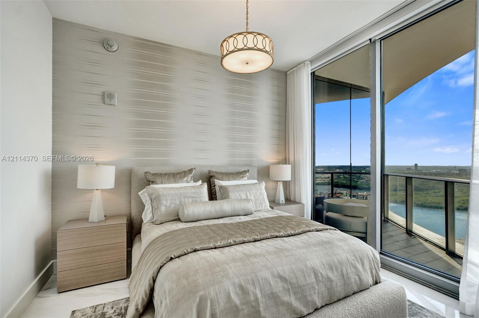 Floor-to-ceiling glass sliding doors, private balcony, textured accent wall, polished stone flooring, and drum pendant lighting