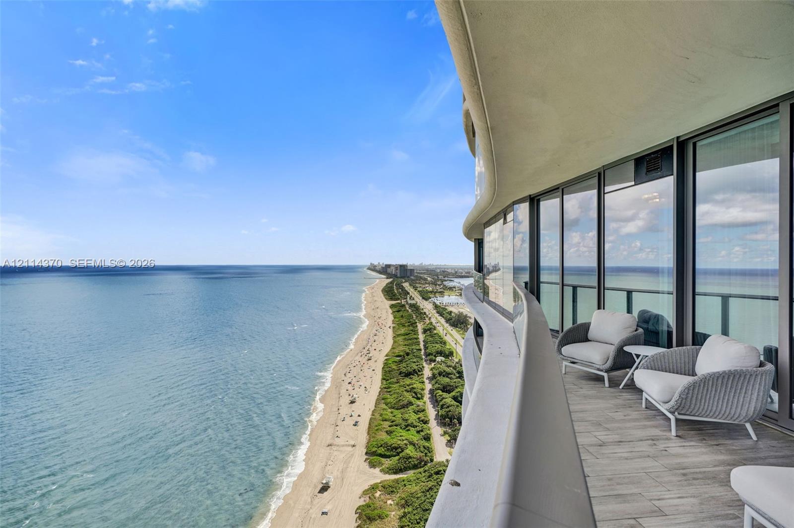 Curved wrap-around balcony with wood-finish tile flooring and floor-to-ceiling glass paneling