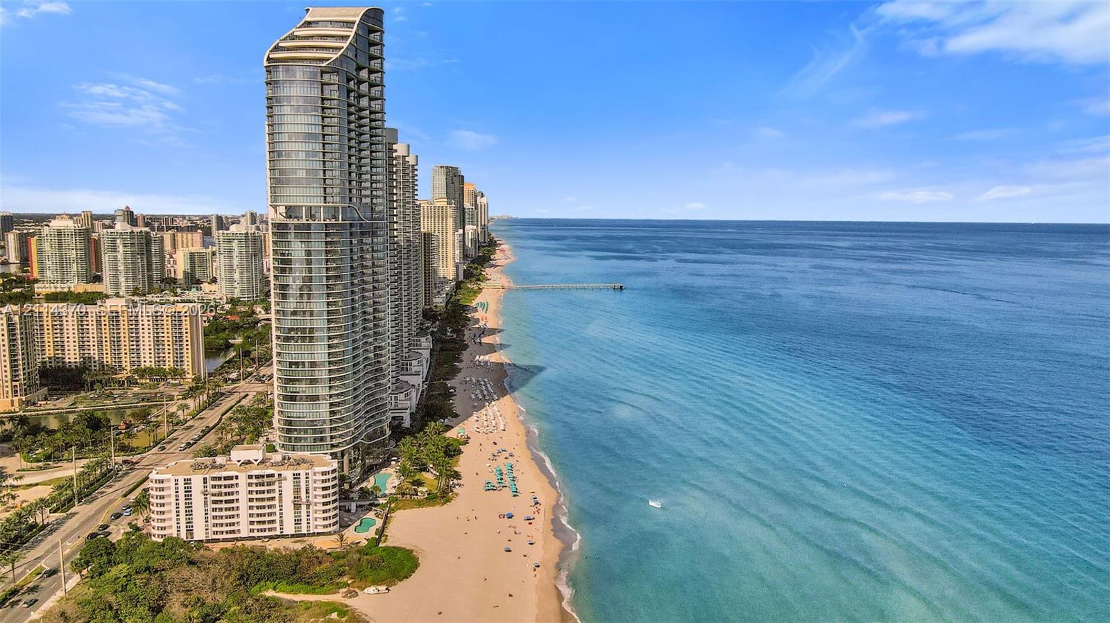 High-rise residential tower featuring glass facade construction, direct oceanfront location, and expansive shoreline access