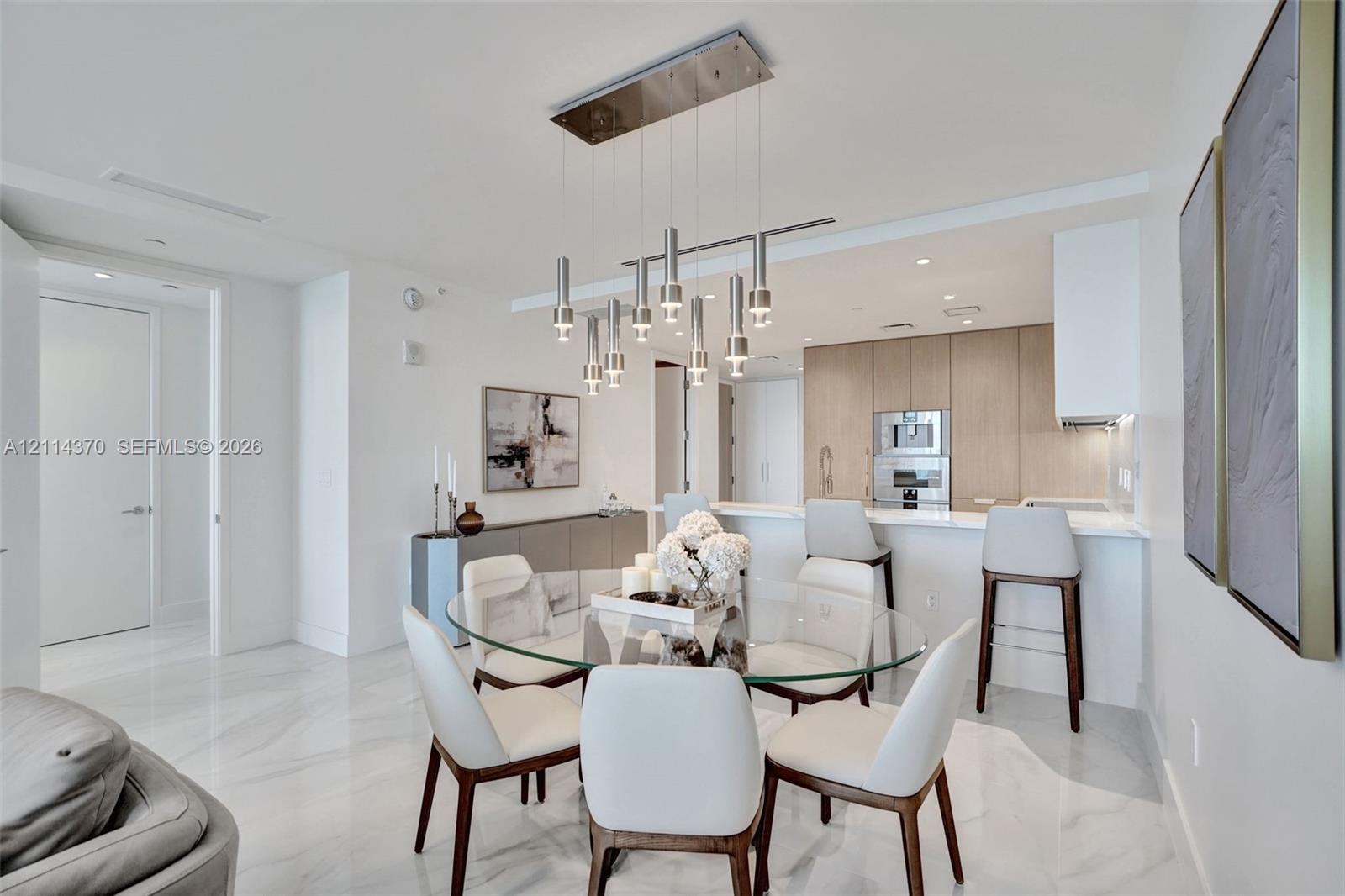 Large-format tile flooring, contemporary multi-pendant lighting fixture, flat-panel cabinetry, and integrated stainless steel appliances
