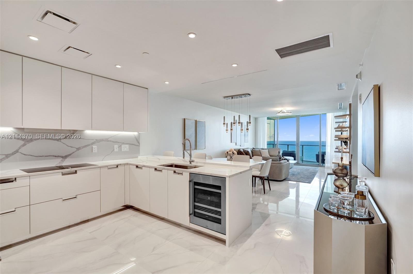 Kitchen featuring flat-panel cabinetry, stone-patterned backsplash, built-in wine refrigerator, under-cabinet lighting, and polished stone-finish flooring