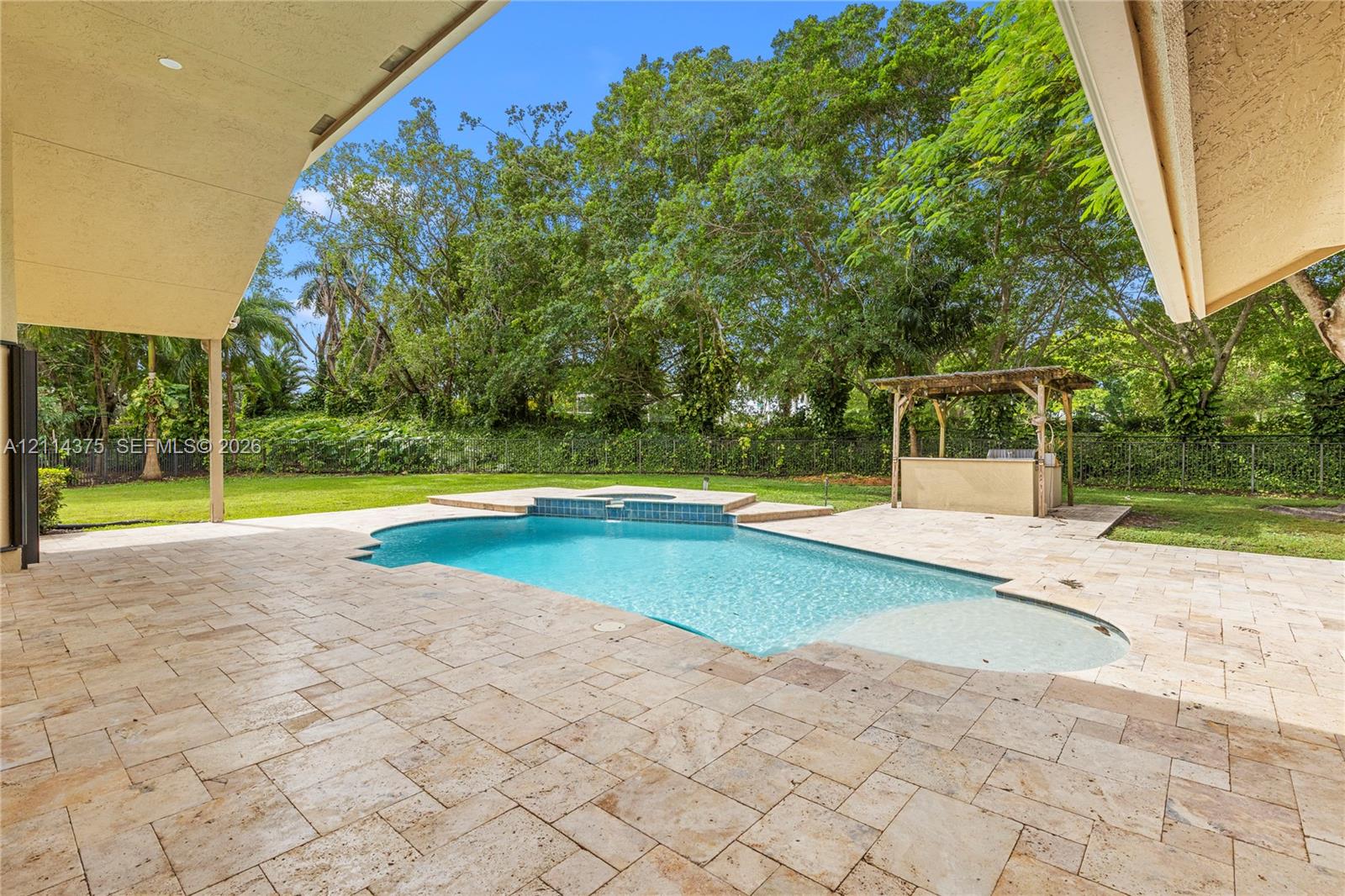 Covered patio featuring stone tile flooring, in-ground swimming pool with built-in spa, and a poolside pergola with an integrated bar