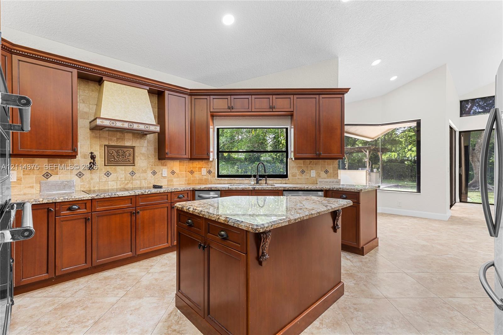 Kitchen featuring stained wood cabinetry, stone countertops, a center island with corbel detailing, a tiled backsplash, and recessed lighting