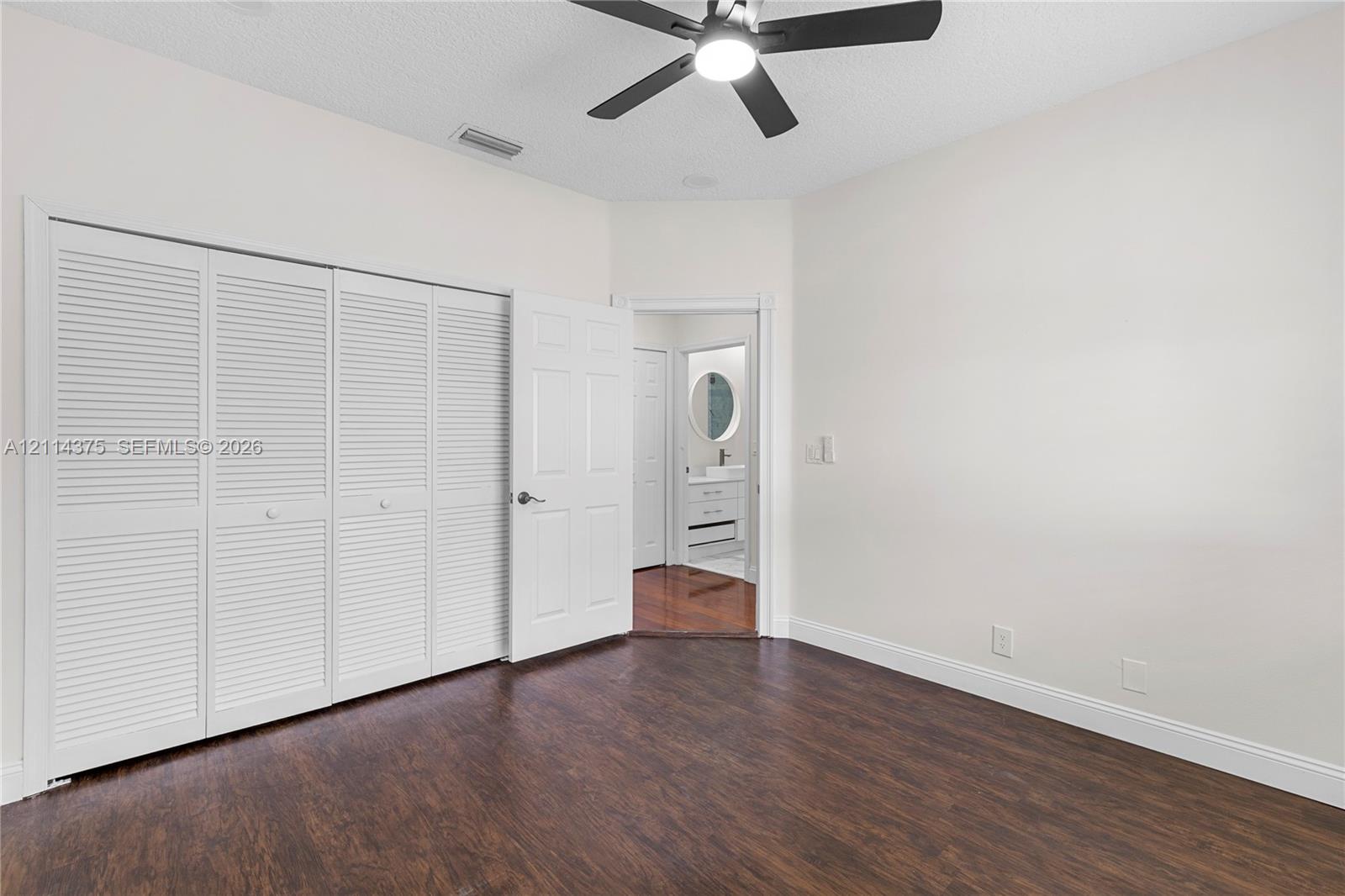 Wood-finish flooring, multi-panel louvered closet doors, and ceiling fan with integrated lighting
