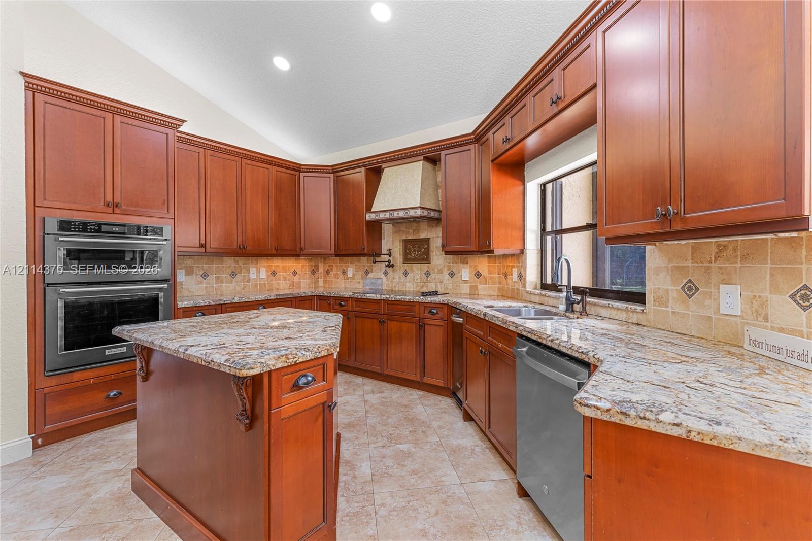 Kitchen featuring wood cabinetry, stone countertops, tiled backsplash, built-in double wall oven, and a center island