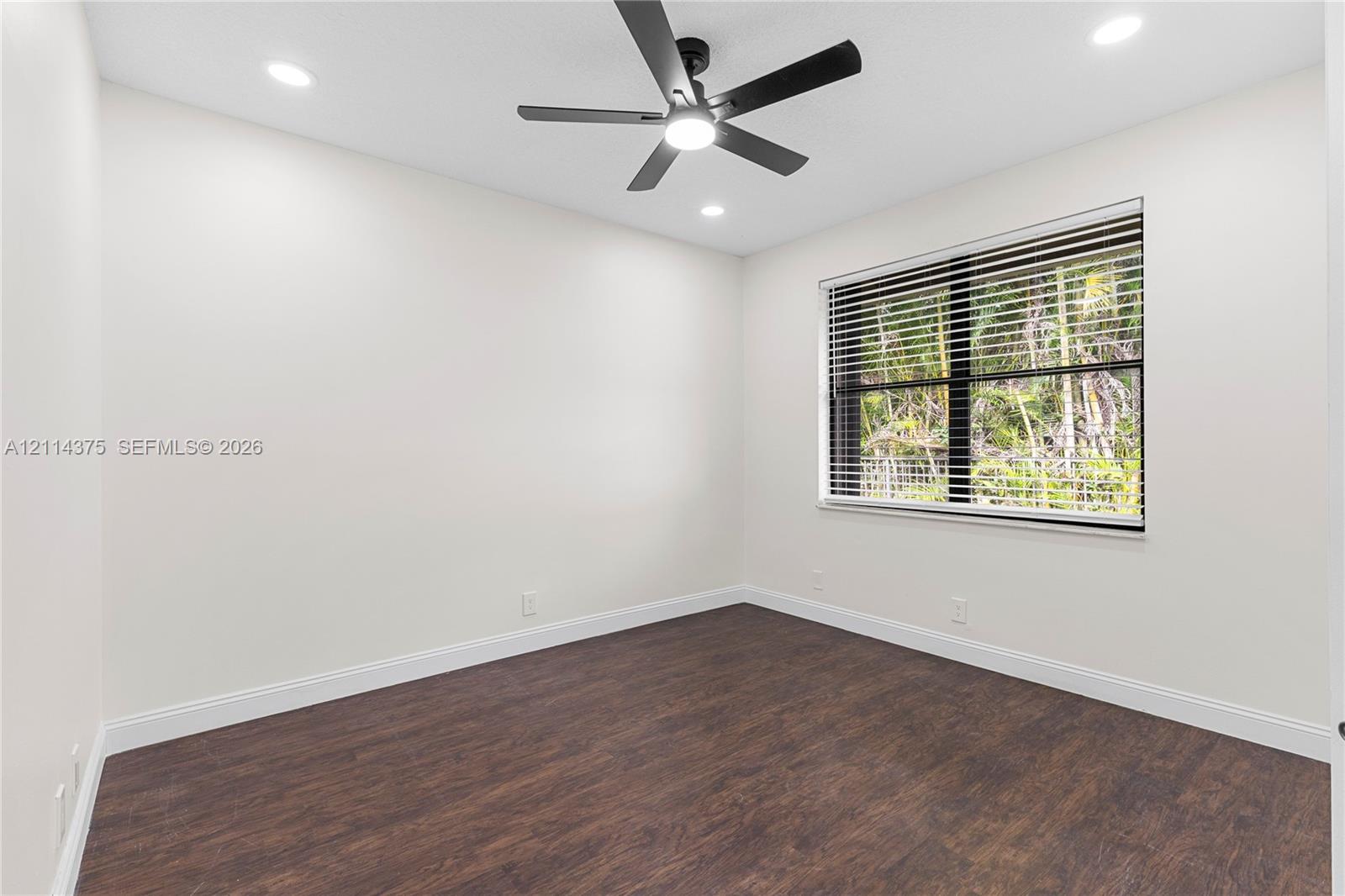 Room featuring wood-finish flooring, recessed lighting, and a multi-blade ceiling fan with integrated lighting