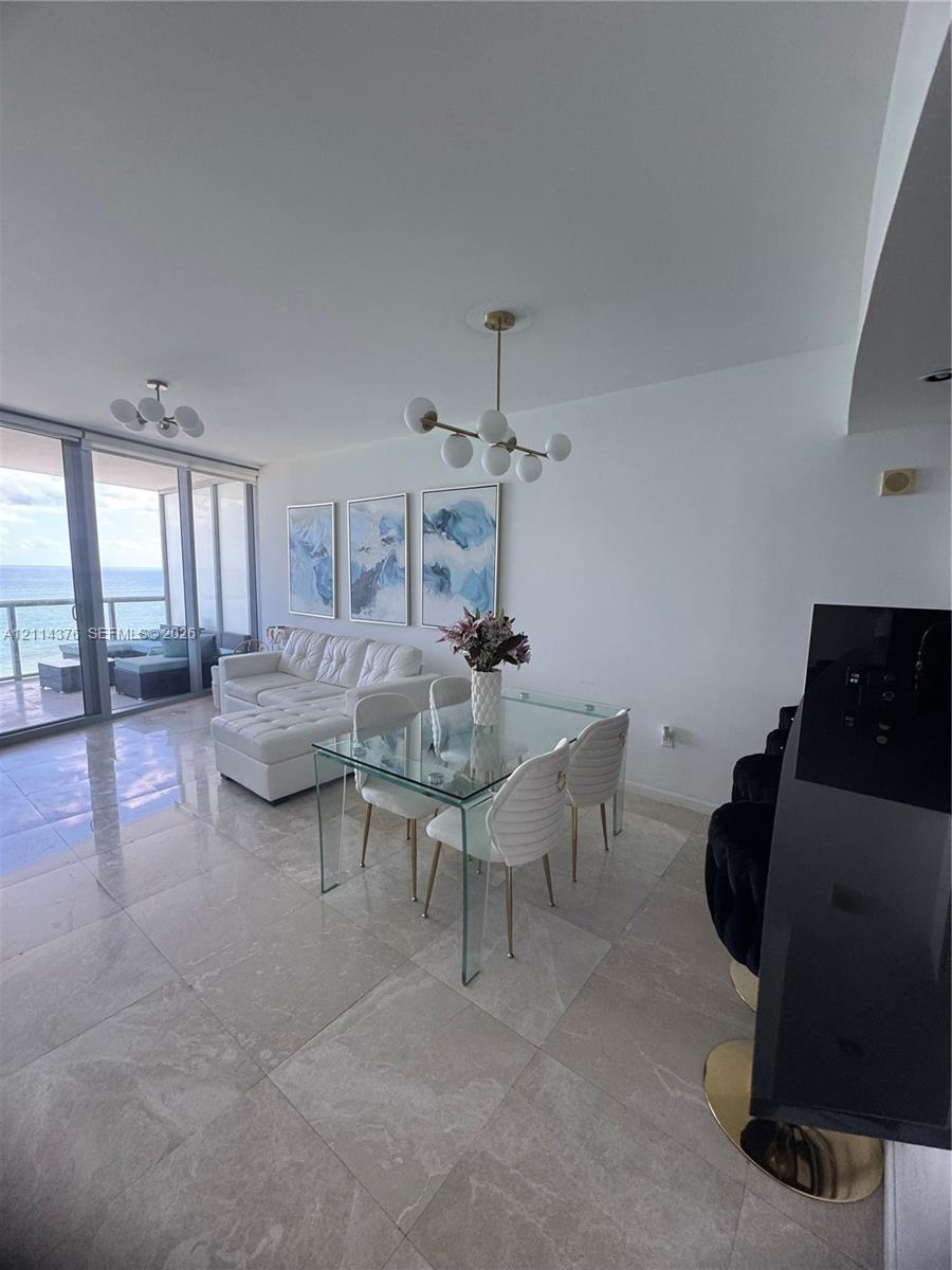 Open-concept interior featuring large-format tile flooring, floor-to-ceiling glass sliding doors, and modern multi-arm globe chandeliers