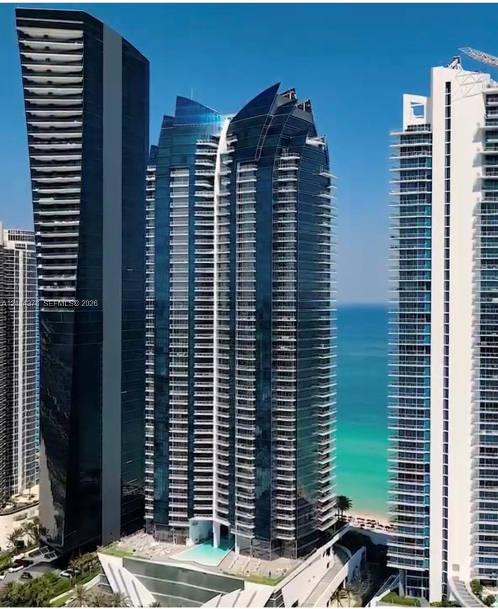 High-rise architectural exterior featuring glass-curtain facade, wrap-around balconies, and coastal frontage