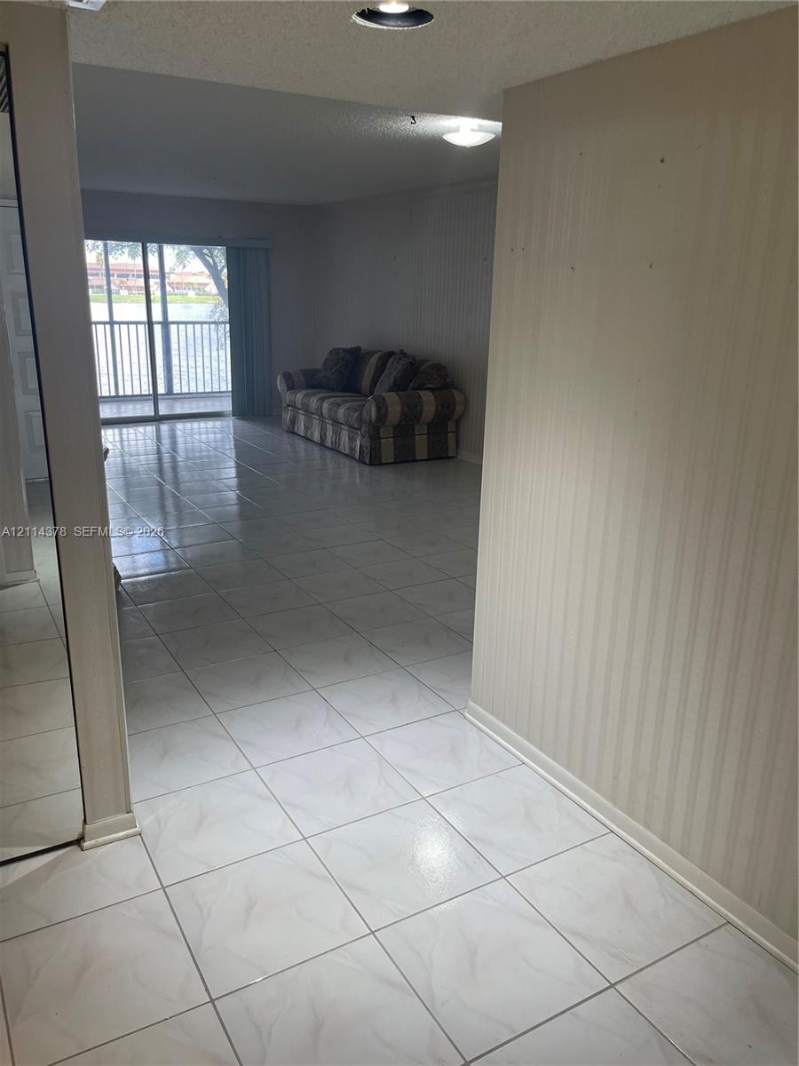 Interior space featuring large-format tile flooring, textured wallpaper, recessed lighting, and a sliding glass door providing external access