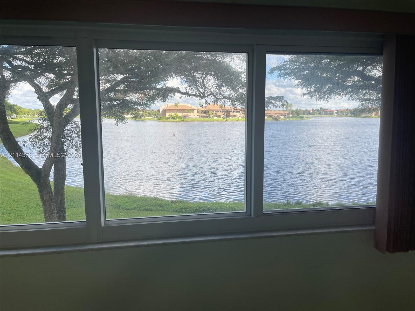 Large multi-pane window featuring white frames, a stone sill, and expansive water frontage
