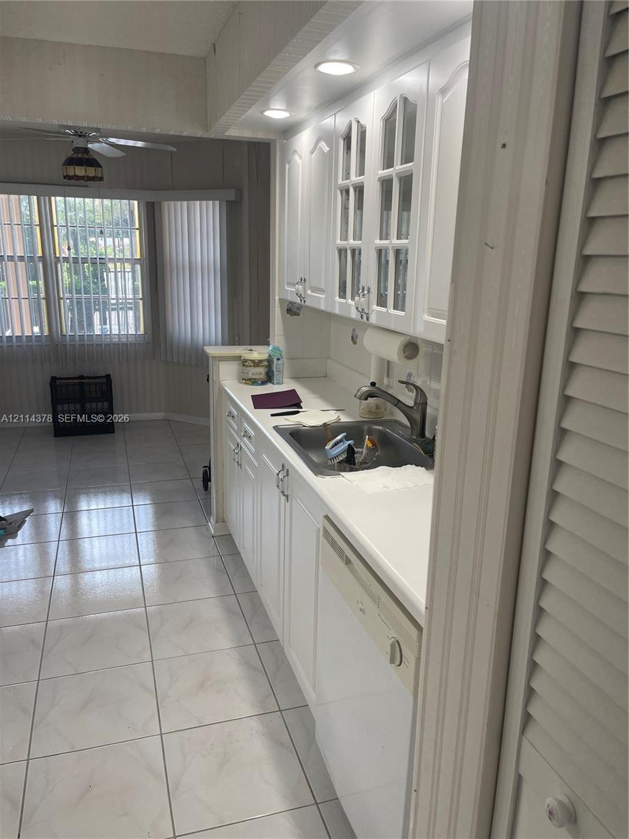 Kitchen featuring white cabinetry with glass-panel upper doors, recessed lighting, tile flooring, and integrated dishwasher