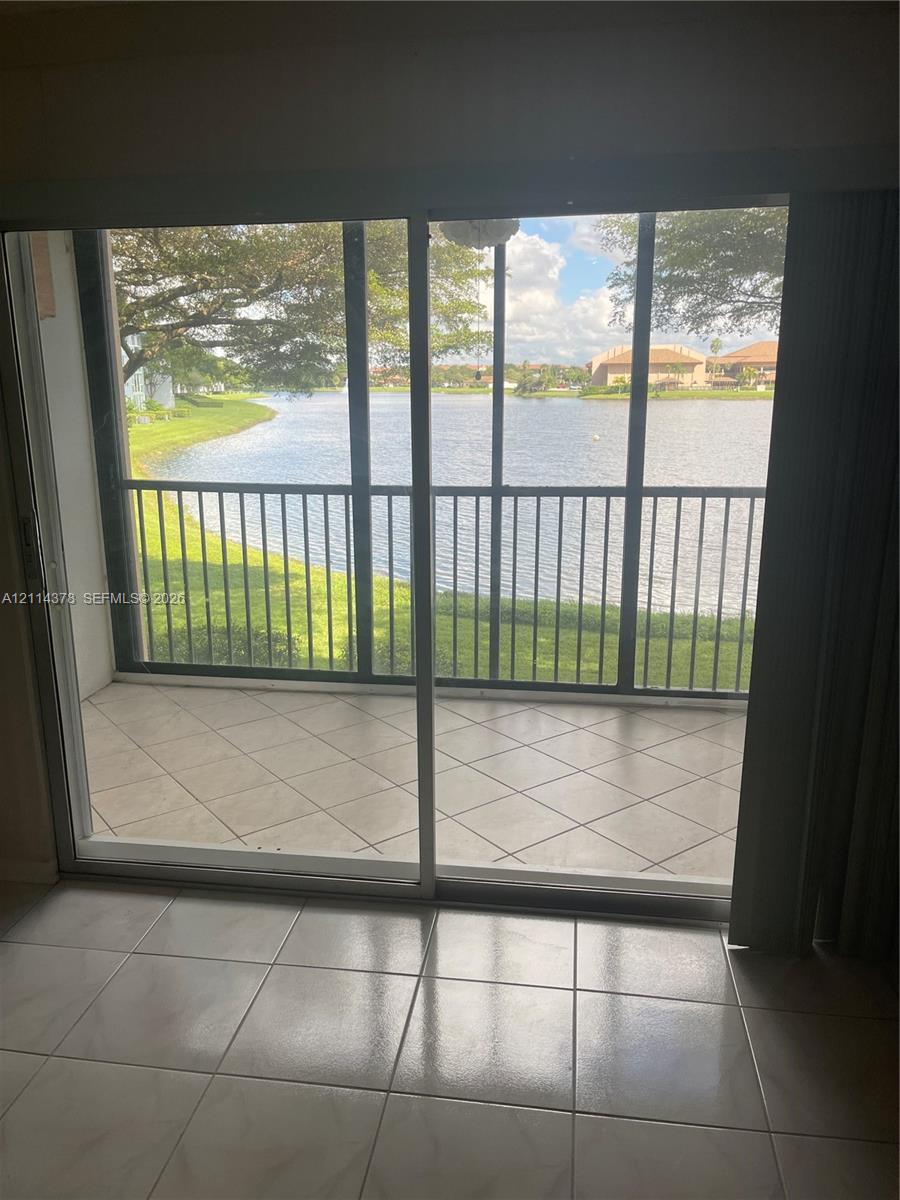 Screened-in balcony featuring tile flooring, metal railings, and direct water frontage