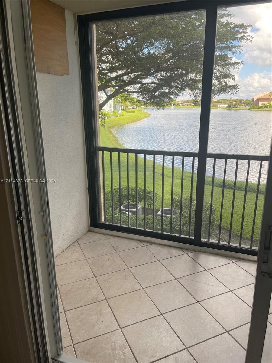 Screened-in balcony featuring ceramic tile flooring, metal railings, and exposure to a water feature