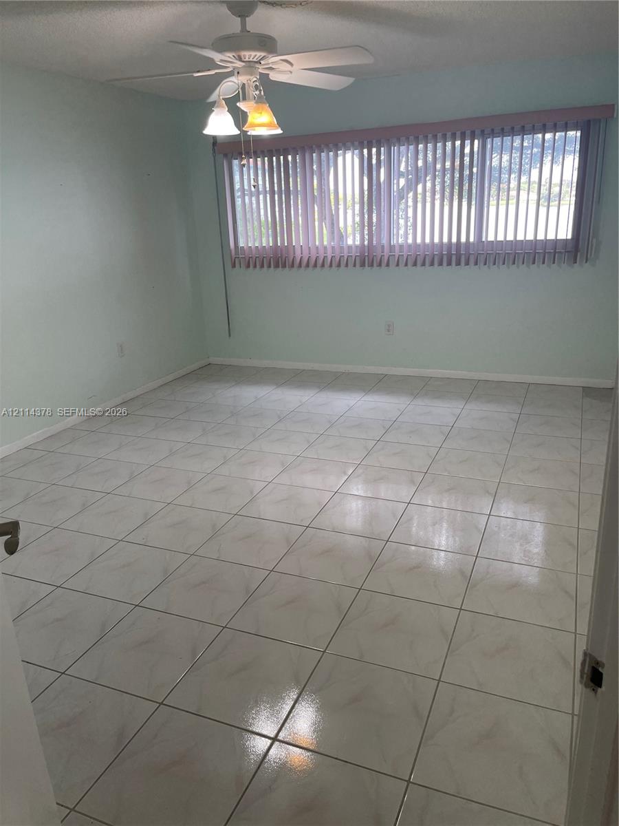 Ceramic tile flooring, multi-light ceiling fan, and large horizontal window with vertical blinds