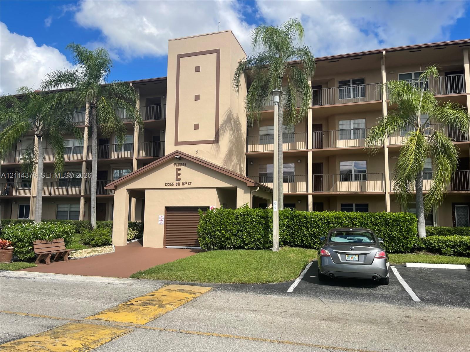 Multi-story stucco exterior featuring private balconies and mature palm tree landscaping