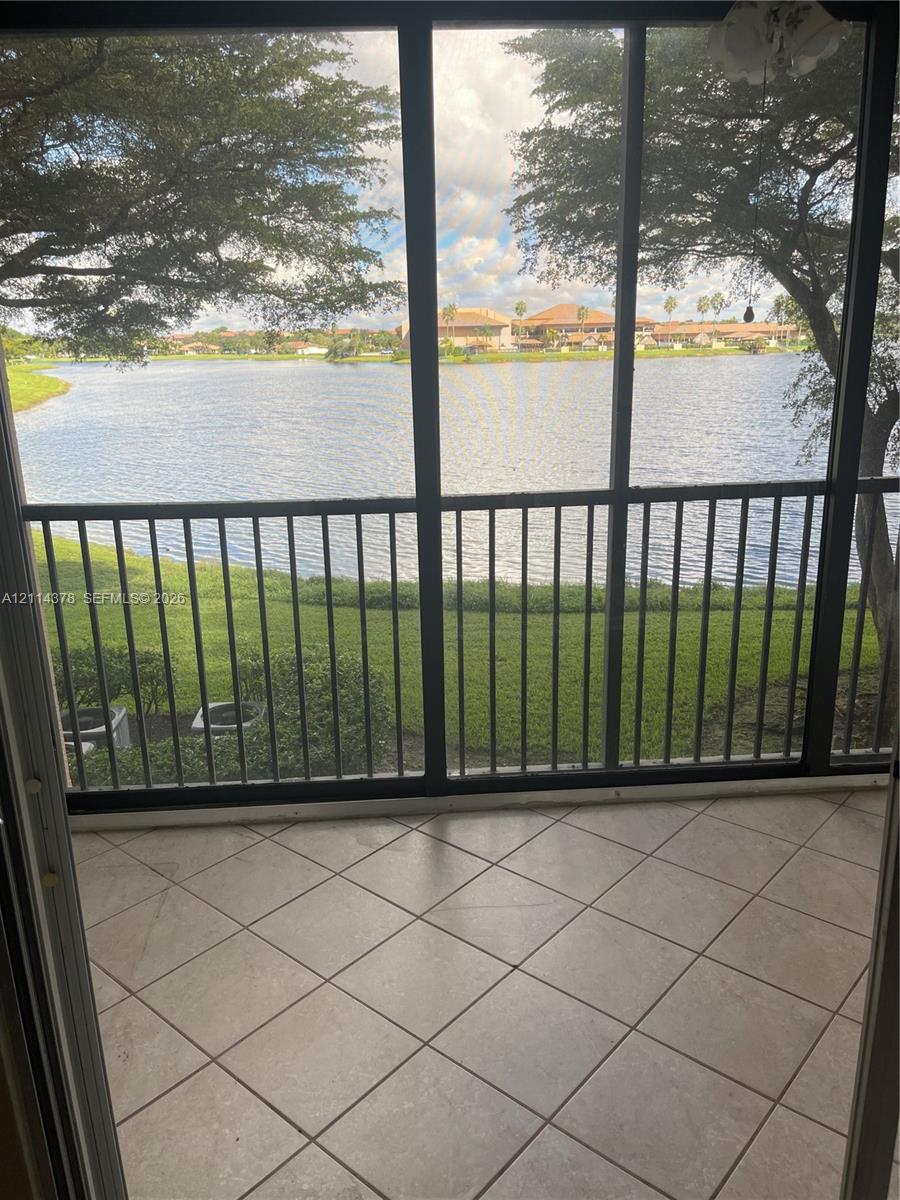 Screened-in patio with neutral tile flooring, metal frame enclosures, and water frontage
