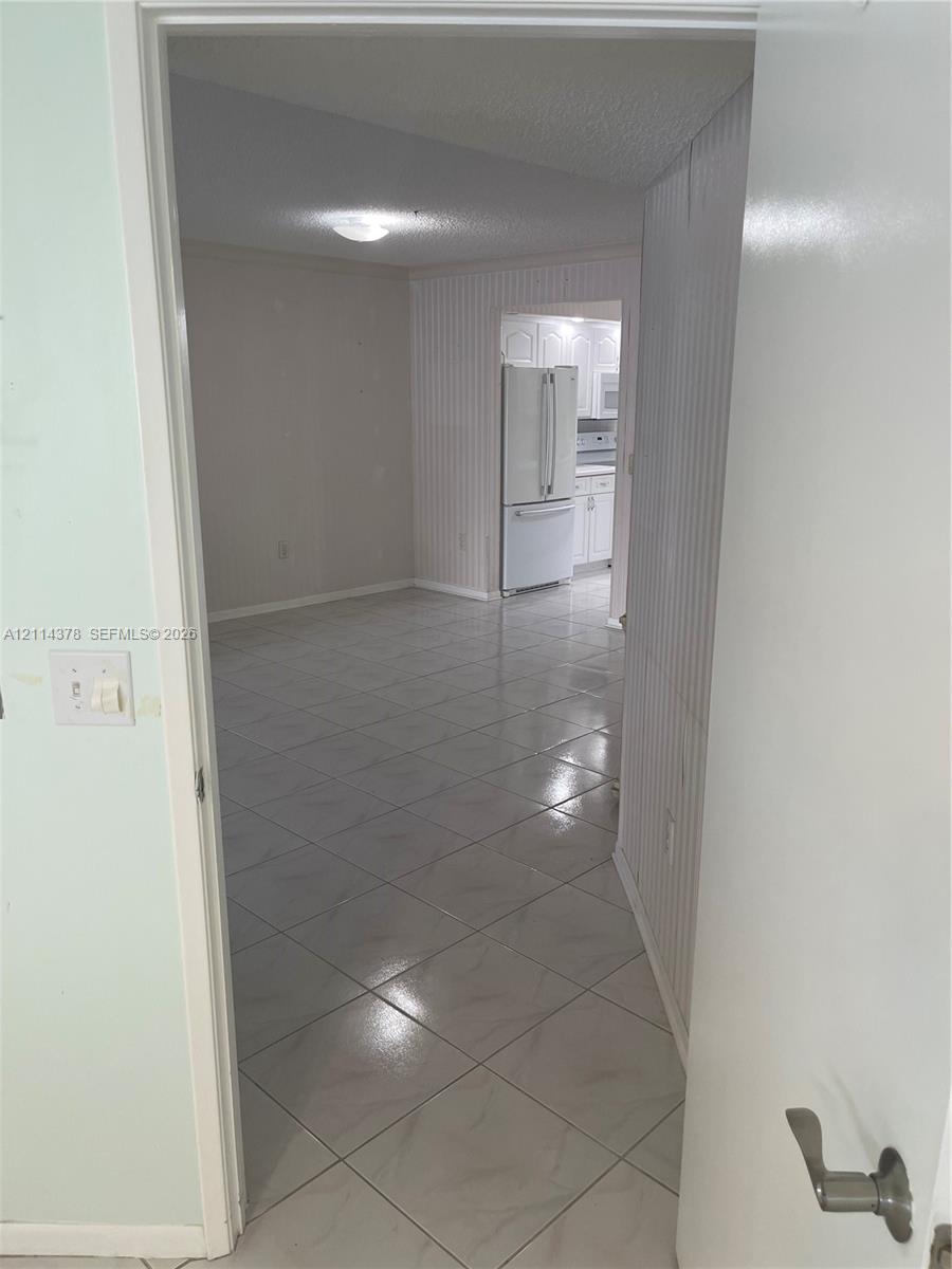 Ceramic tile flooring, white wainscoting wall paneling, and flush-mount lighting fixtures