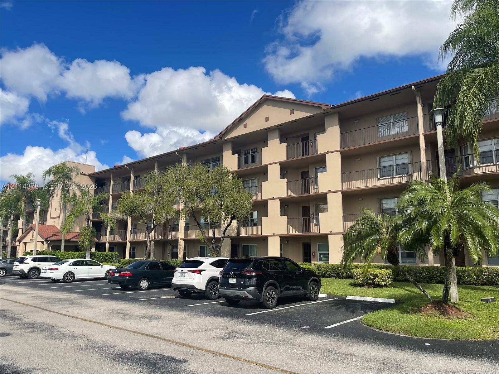 Multi-story building exterior featuring stucco siding, gabled roofline, and private balconies with metal railings