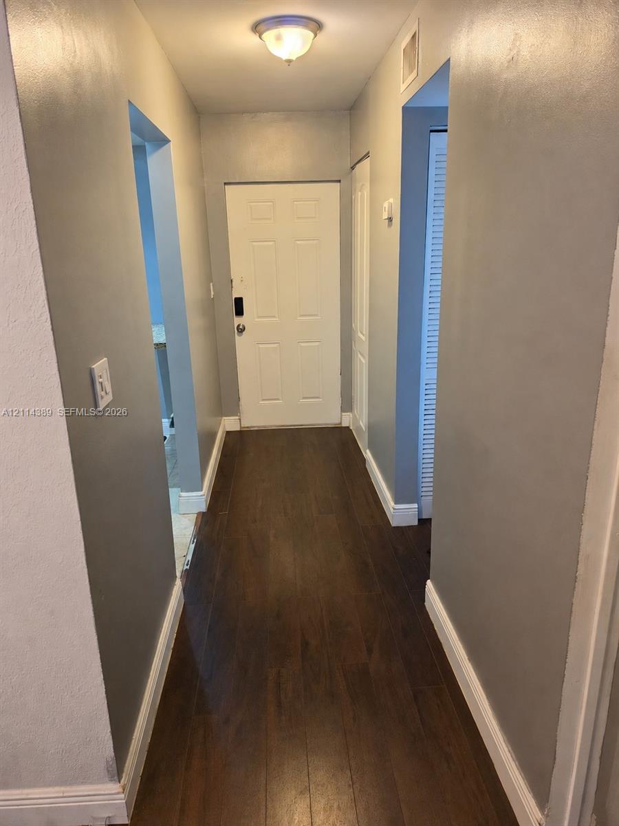 Entryway featuring wood-finish flooring, a six-panel door, neutral wall paint, and a flush-mount ceiling light