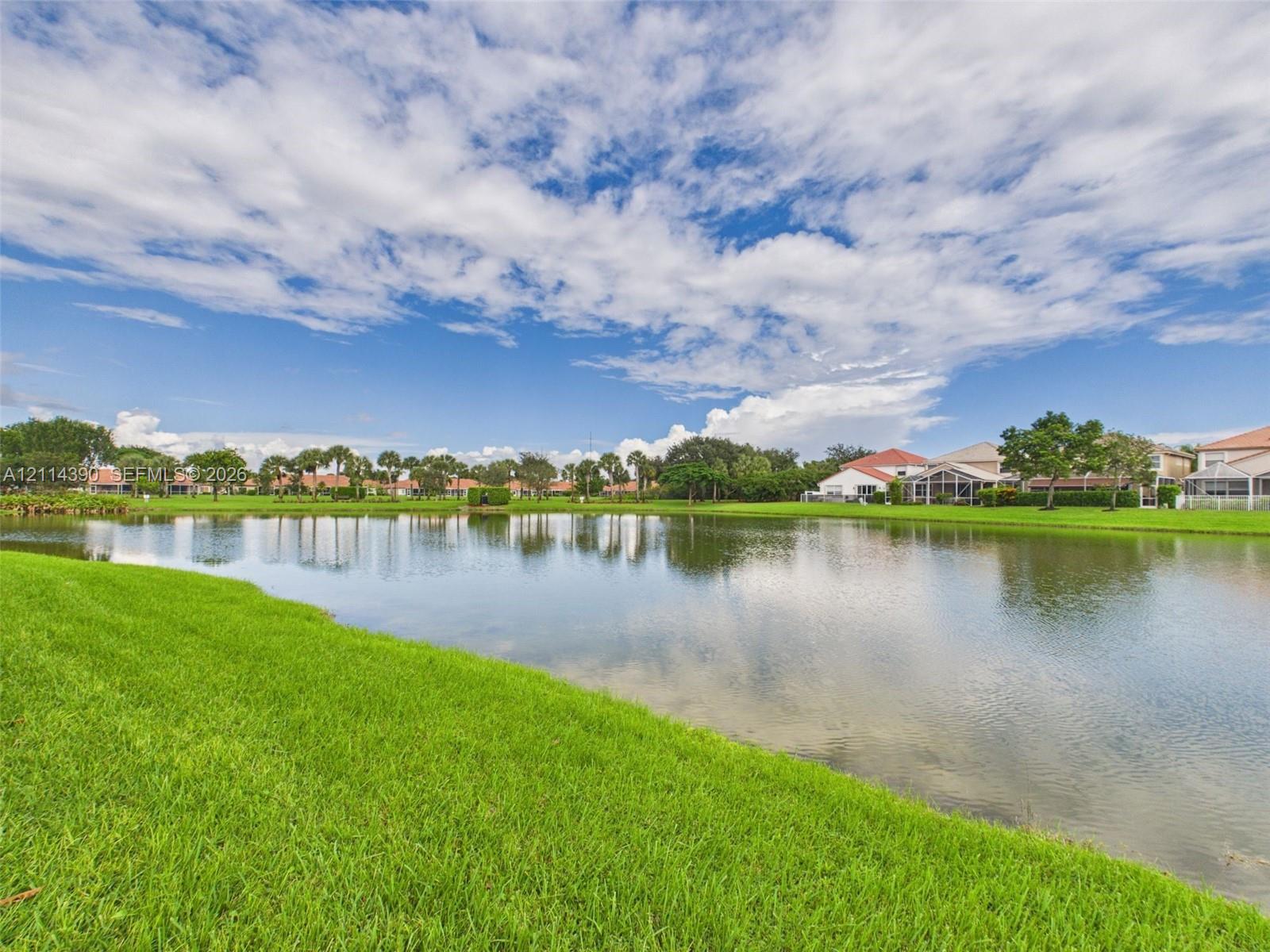 Waterfront property featuring a manicured lawn, mature trees, and natural landscaping