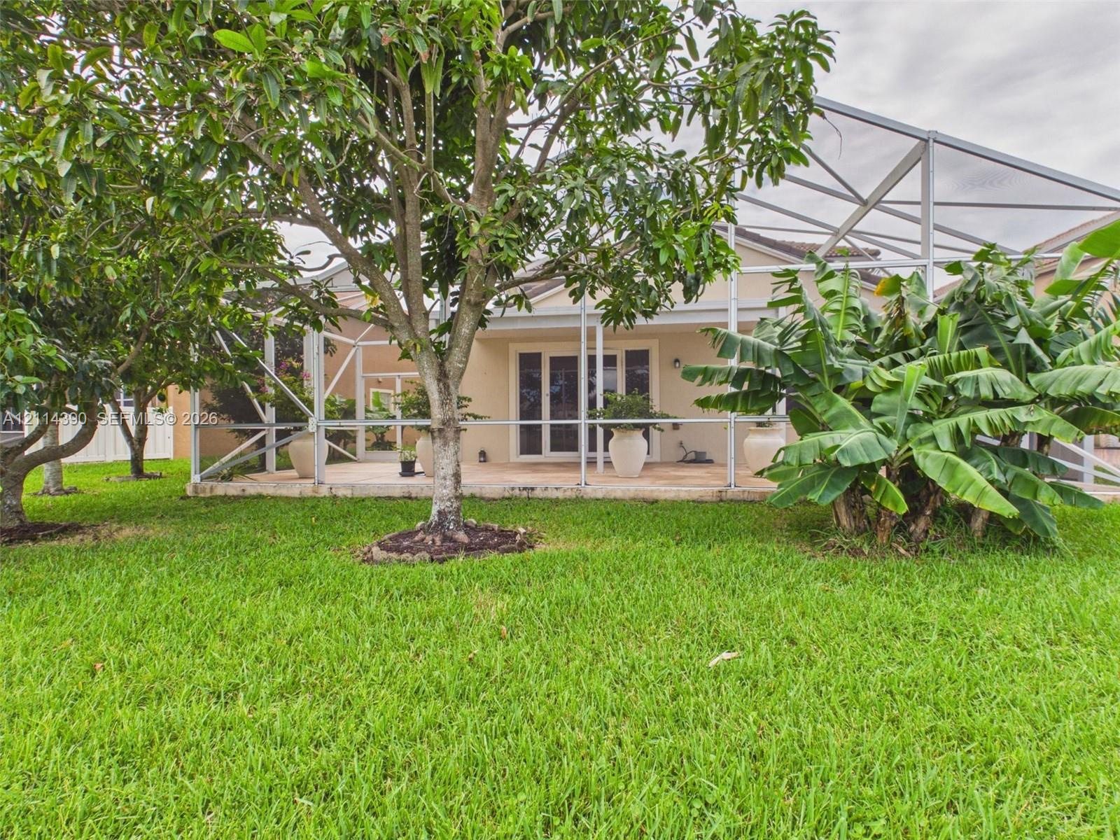 Screen-enclosed patio featuring a paver surface, established trees, and mature landscaping