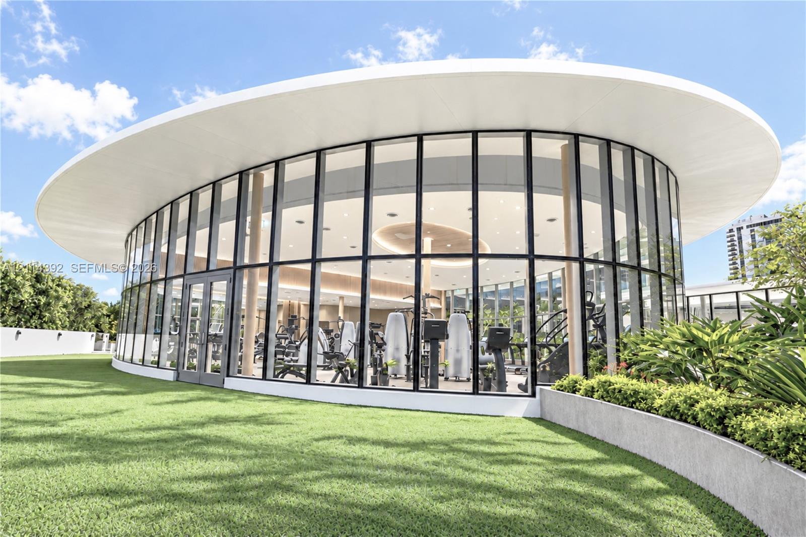 Elliptical glass-walled structure featuring floor-to-ceiling windows, a sweeping overhanging roofline, and integrated recessed lighting