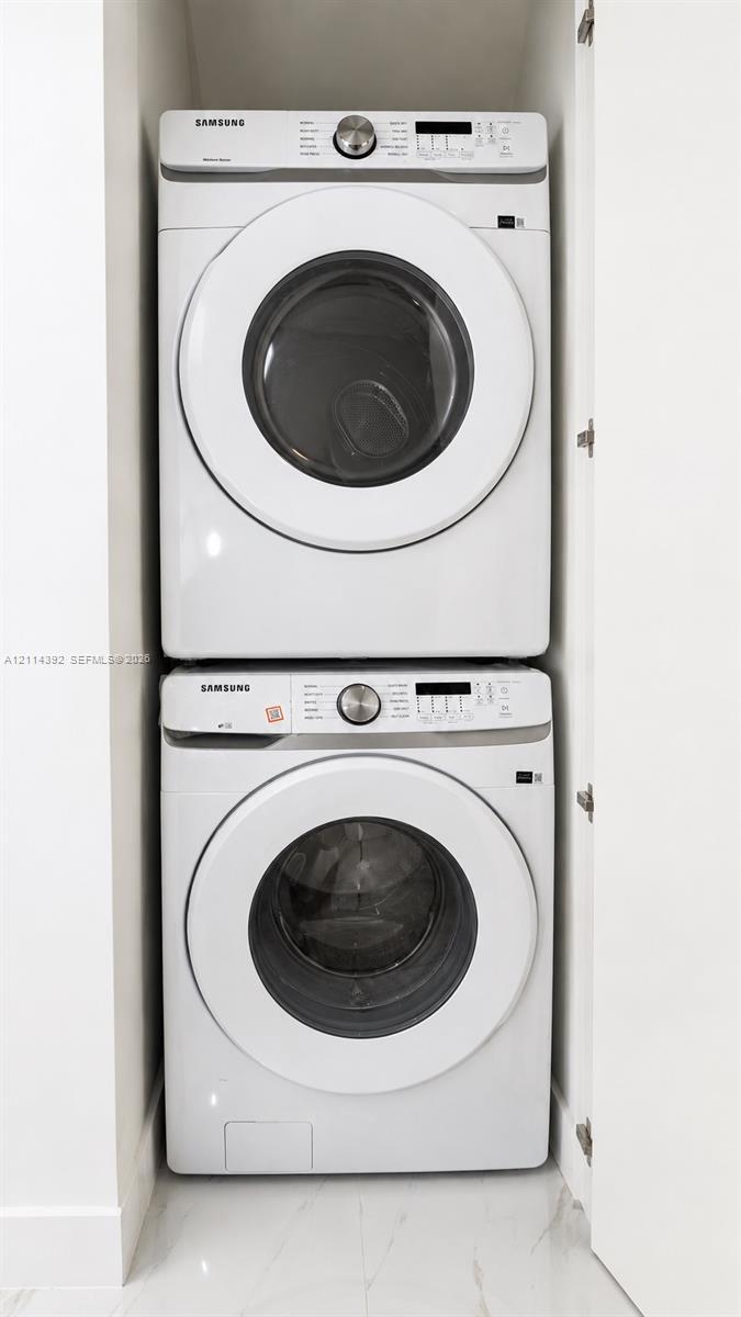 Stacked white Samsung front-loading laundry units housed within a dedicated closet