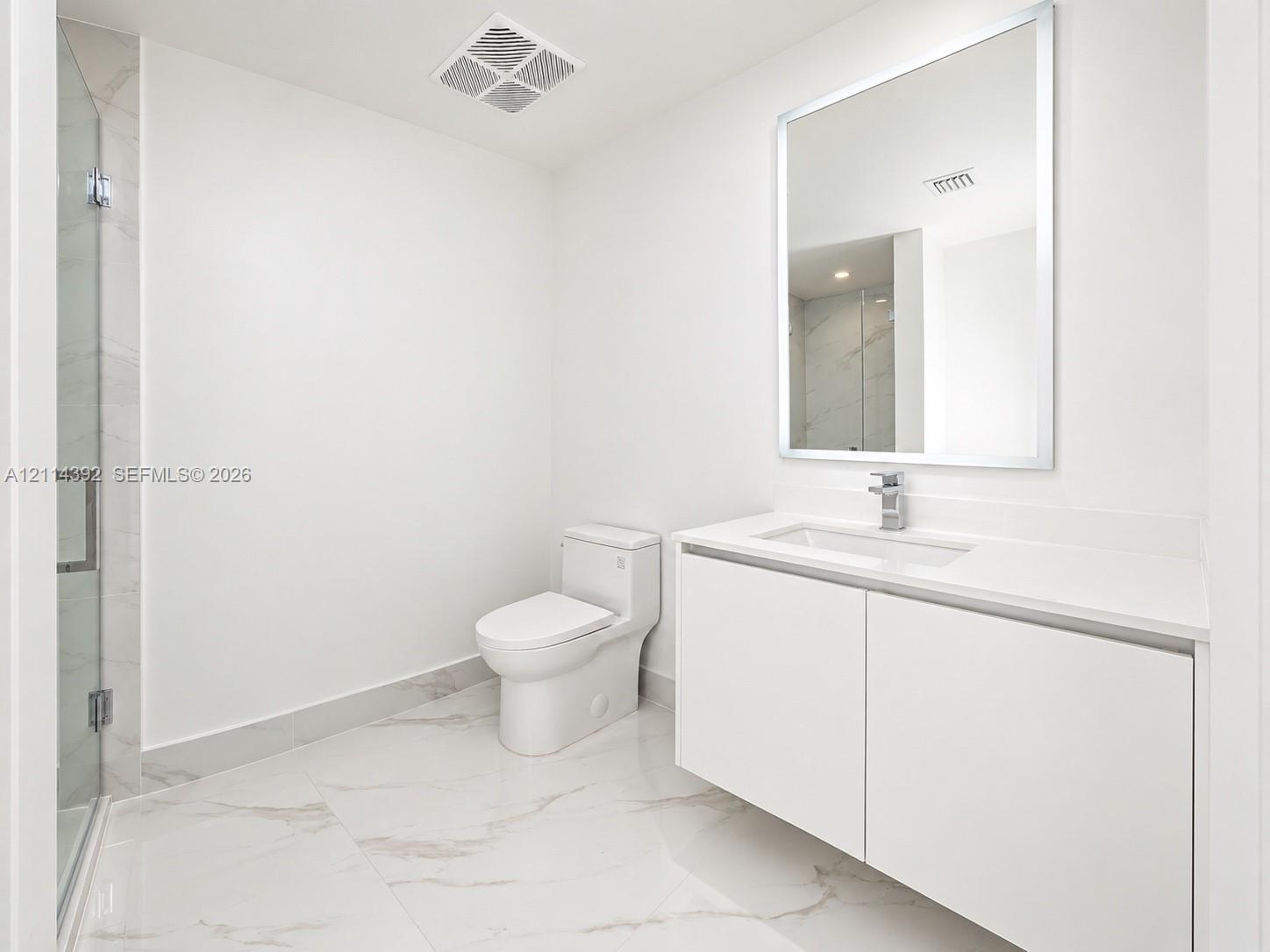 Modern bathroom featuring a floating vanity with a seamless countertop, rectangular sink, polished-edge mirror, and floor-to-ceiling tiled shower with a frameless glass door