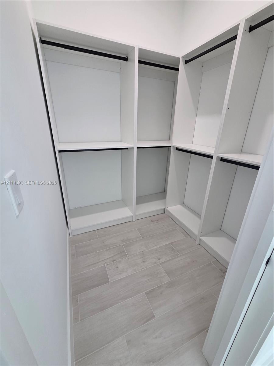 Custom white built-in shelving, integrated hanging rods, and wood-finish tile flooring