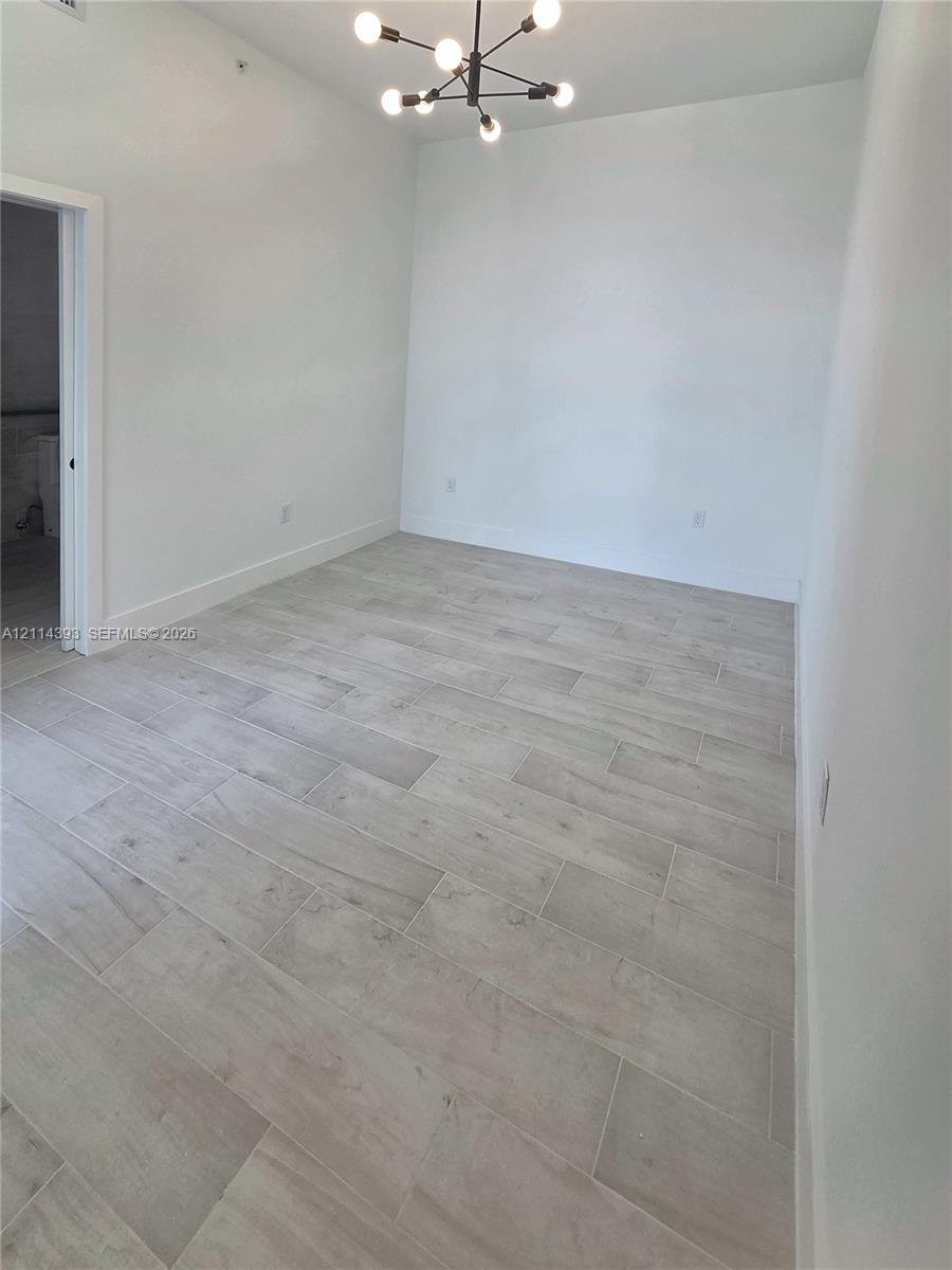 Room interior featuring light-toned tile flooring, neutral walls, and a modern multi-arm light fixture