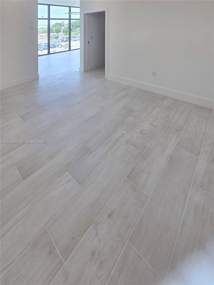 Interior space featuring wood-finish tile flooring, neutral wall tones, and floor-to-ceiling multi-pane glass panels