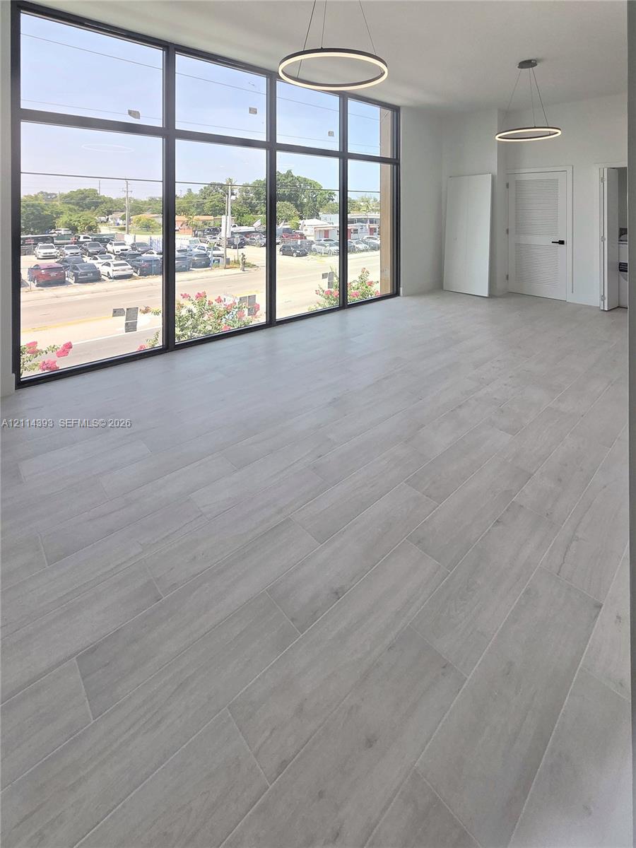 Floor-to-ceiling windows featuring black framing, wood-finish flooring, and minimalist circular pendant lighting