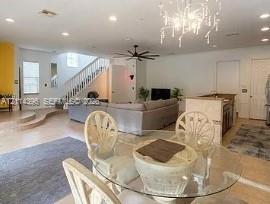 Open floor plan featuring recessed lighting, a multi-tier staircase with a white balustrade, a stone-top kitchen island, and a decorative multi-arm chandelier