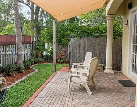 Covered brick paver patio featuring a fabric shade sail and a classic architectural column