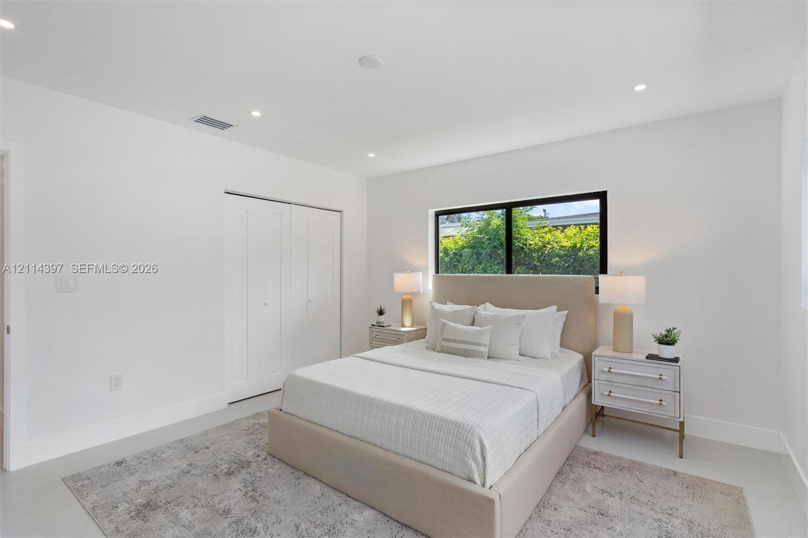 Bright interior space featuring neutral walls, recessed lighting, polished flooring, a large window with black framing, and a double-door reach-in closet