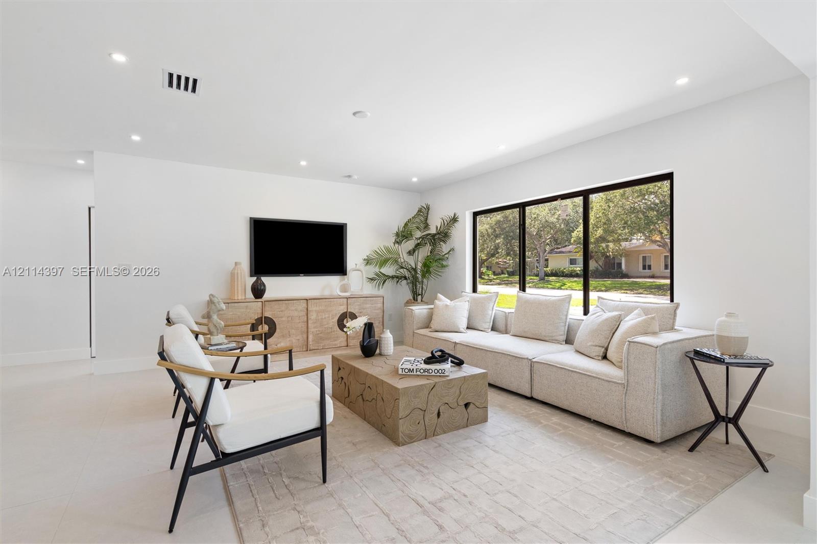 Living area featuring recessed ceiling lighting, light-toned tile flooring, and a large black-framed picture window