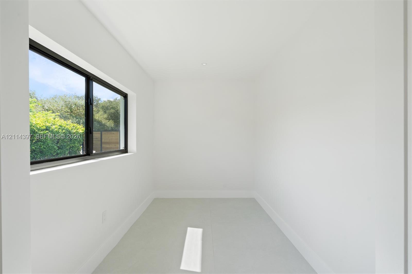 Minimalist interior space featuring large-format tile flooring, high-contrast dark-framed windows, and recessed ceiling lighting