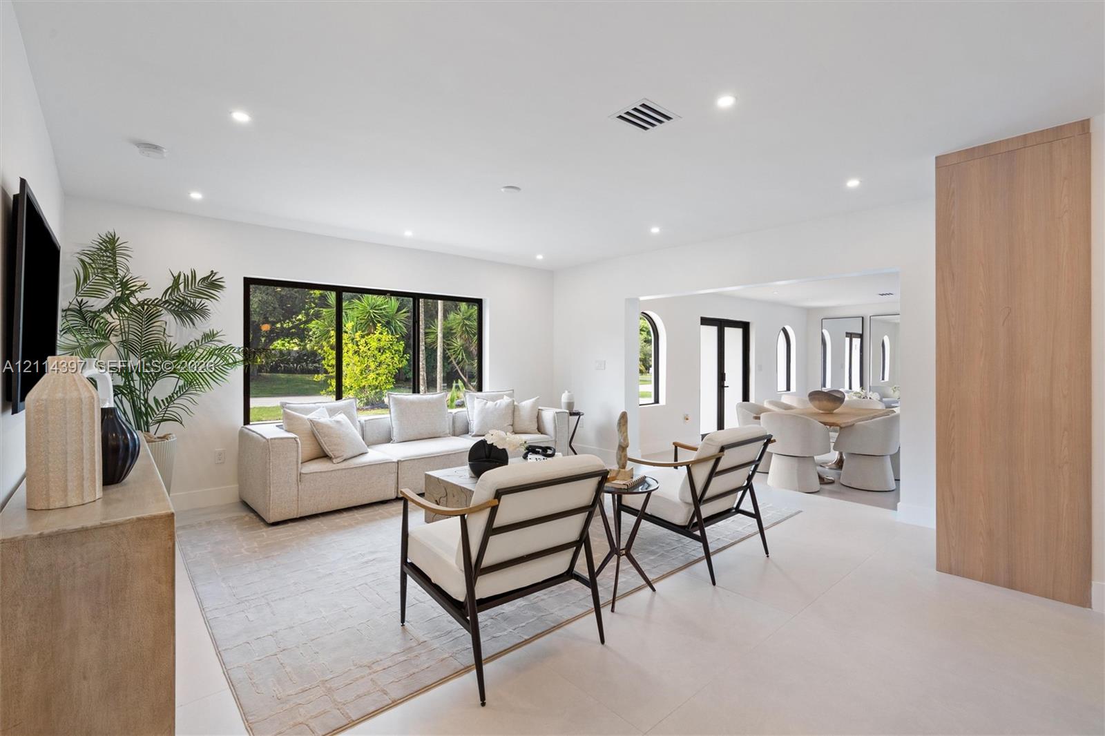 Living space featuring recessed lighting, large-format tile flooring, a wide window with dark framing, and a floor-to-ceiling wood-finish paneled wall