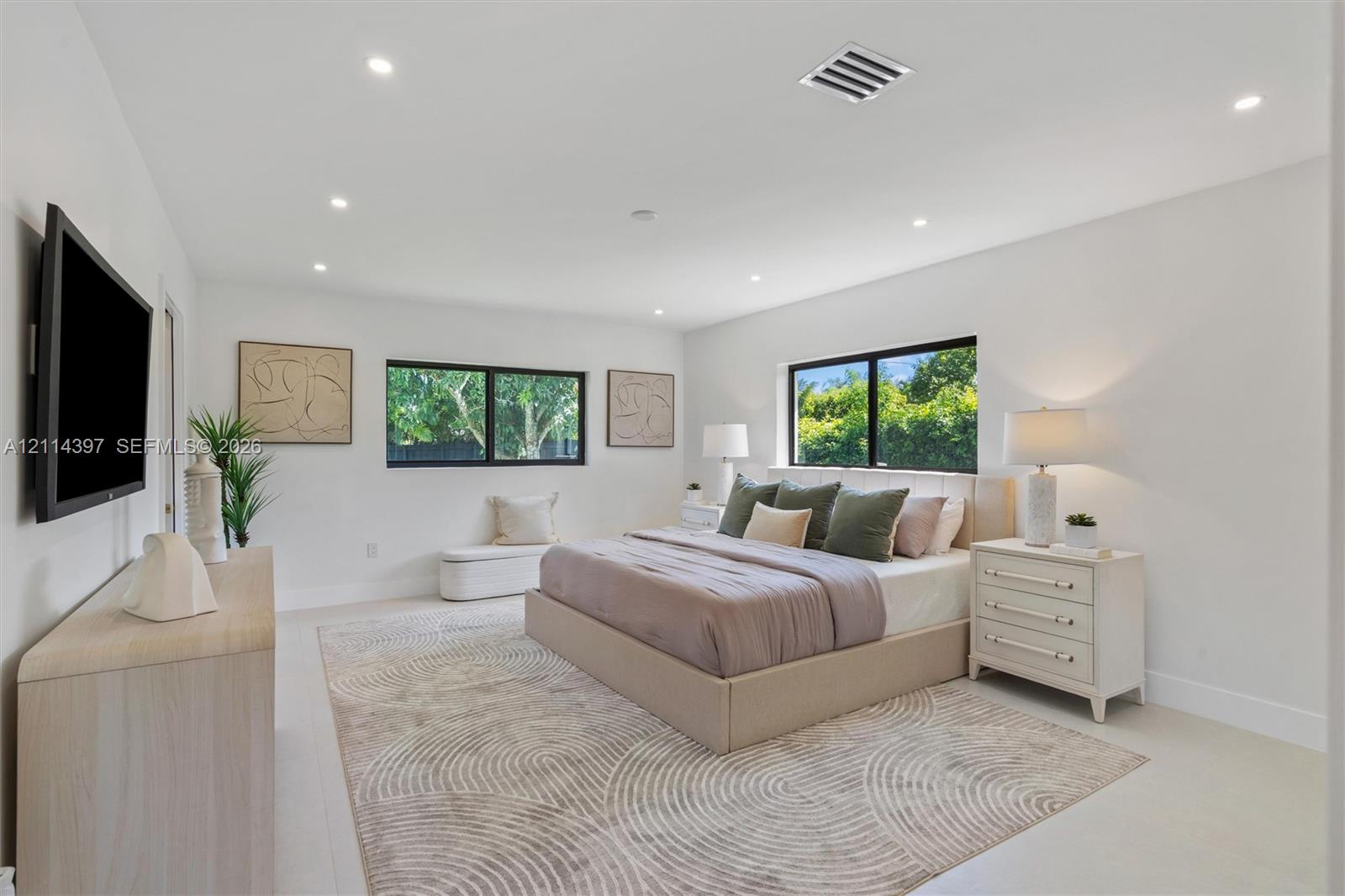 Neutral interior space featuring recessed ceiling lighting, large black-framed windows, and light-toned flooring