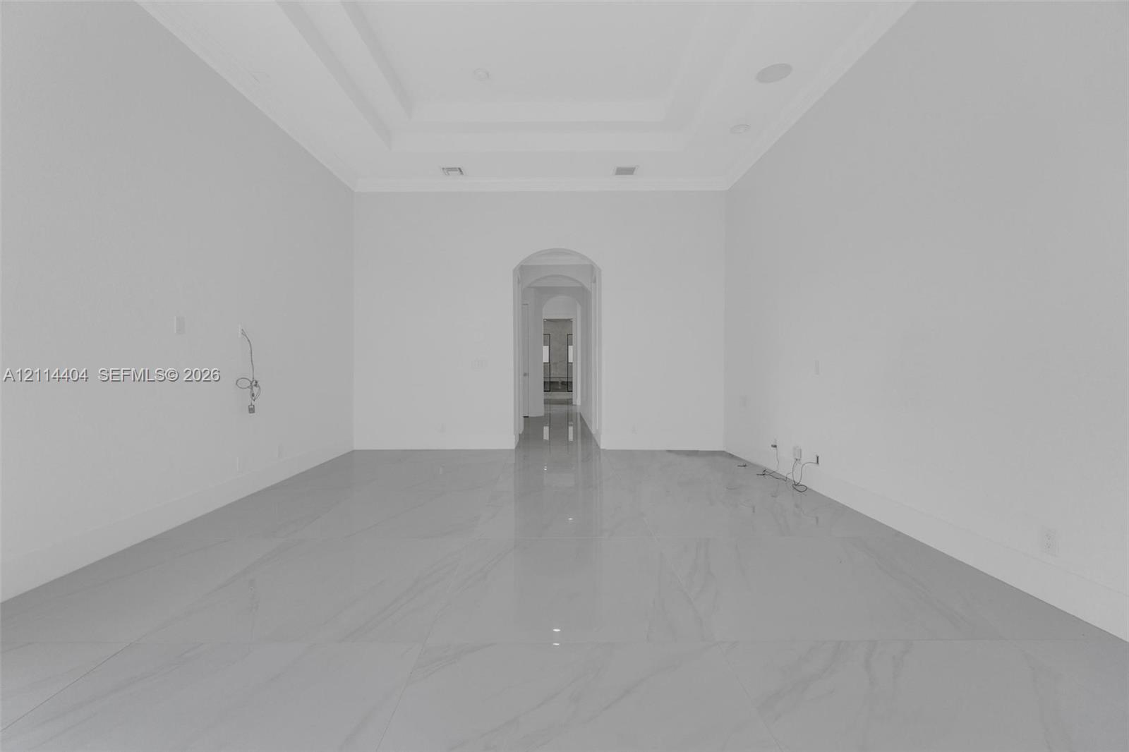 Large format tile flooring, recessed ceiling tray, and arched architectural pass-through