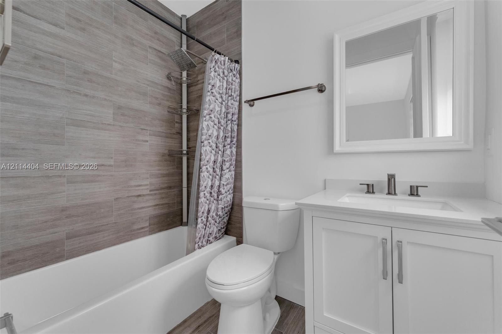Bathroom featuring a white vanity cabinet with a solid surface countertop, rectangular undermount sink, rainfall shower head, and full-height wall tiling