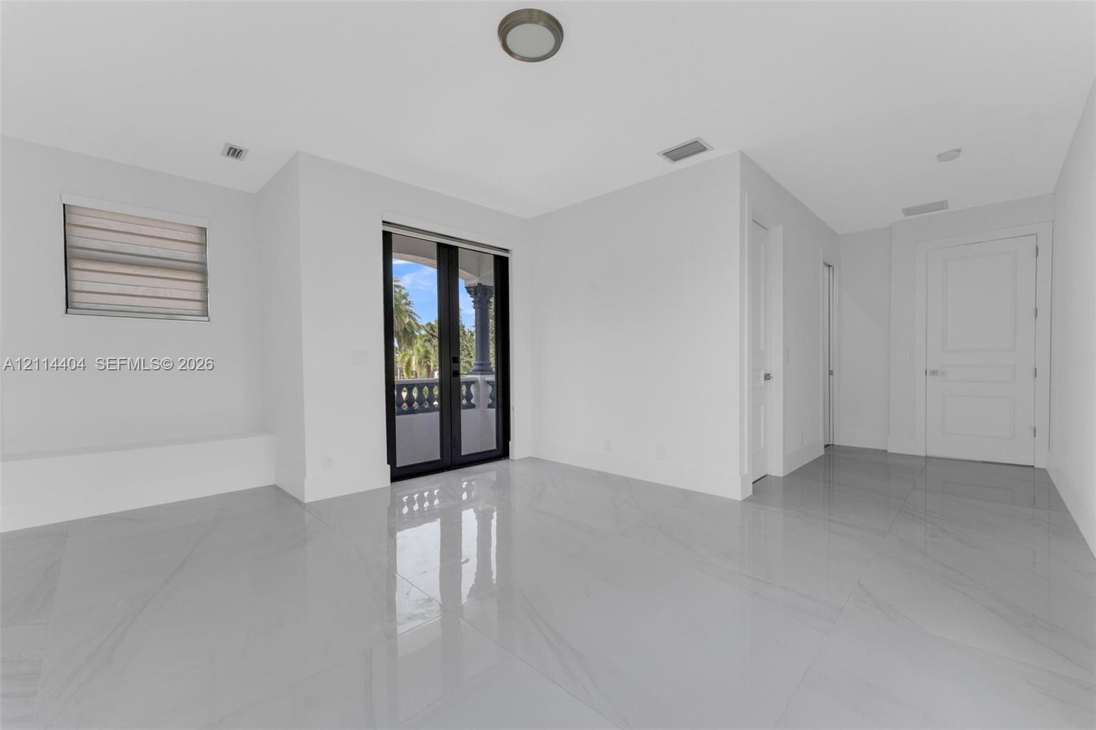 Large-format tile flooring, dual black-framed glass panel doors, recessed ceiling lighting, and solid-core interior doors