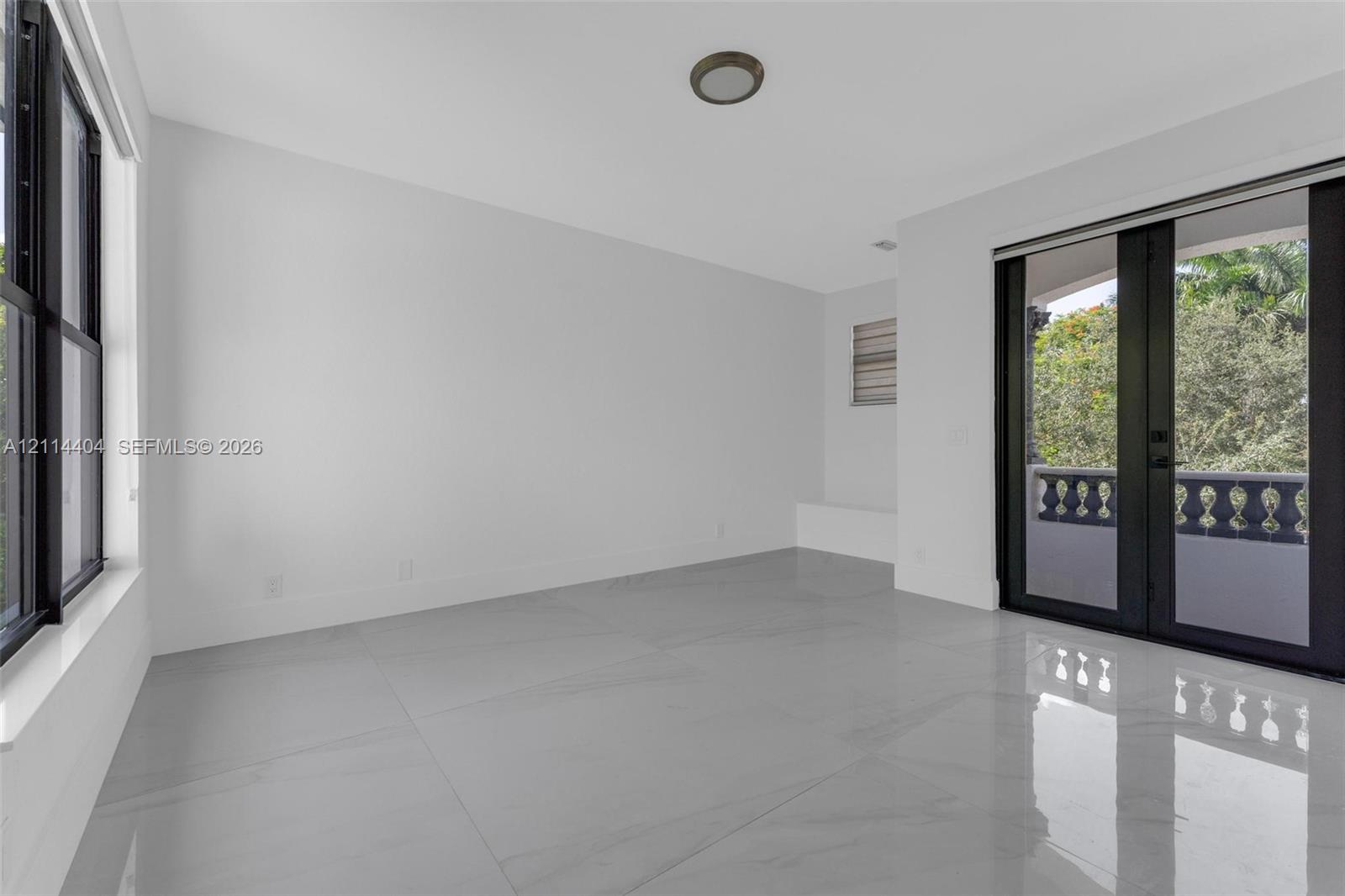 Glossy large-format tile flooring, black-framed windows, glass-paned double doors, and a stone balustrade exterior railing