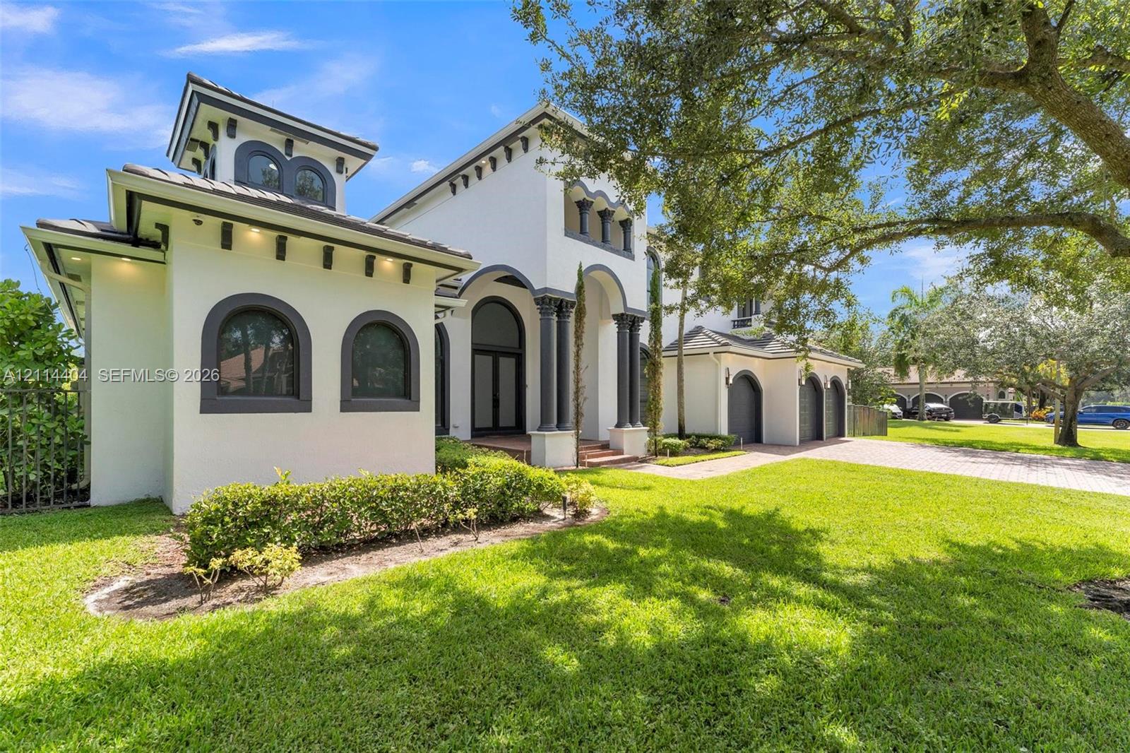 Stucco exterior featuring arched windows, decorative corbels, multi-car garage, and columns at the entryway Stucco exterior featuring arched windows, decorative corbels, multi-car garage, and columns at the entryway