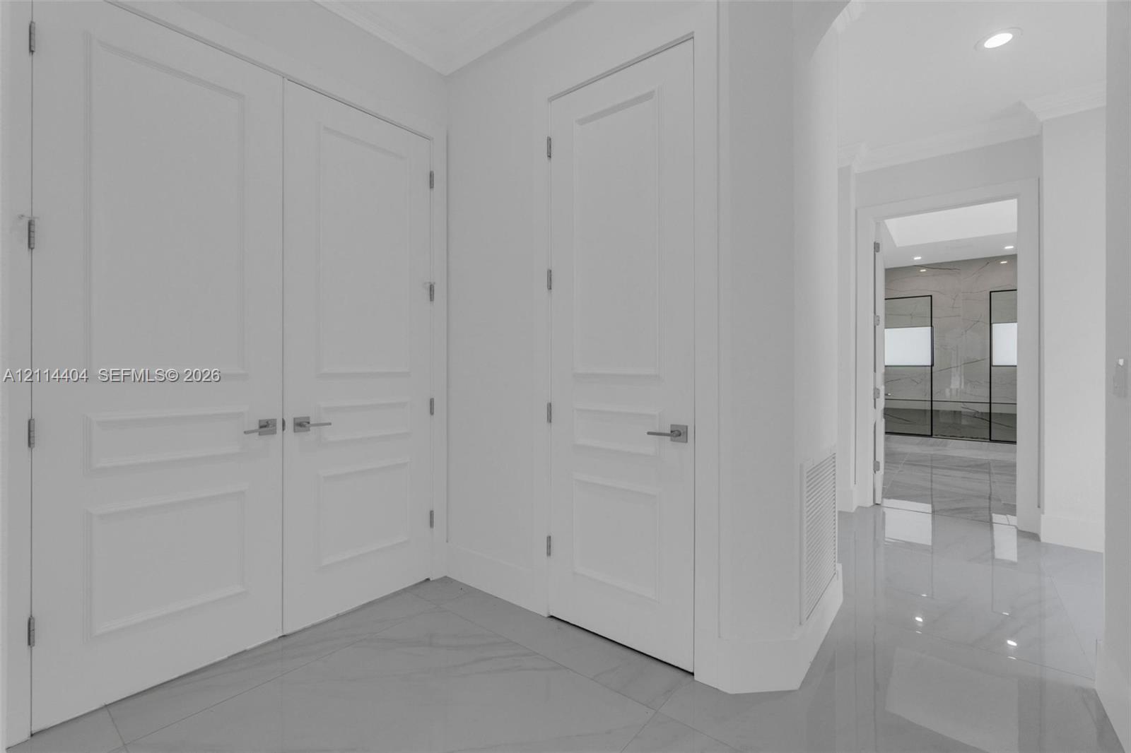 Polished large-format tile flooring, double-panel doors, and single-panel interior doors with brushed nickel hardware