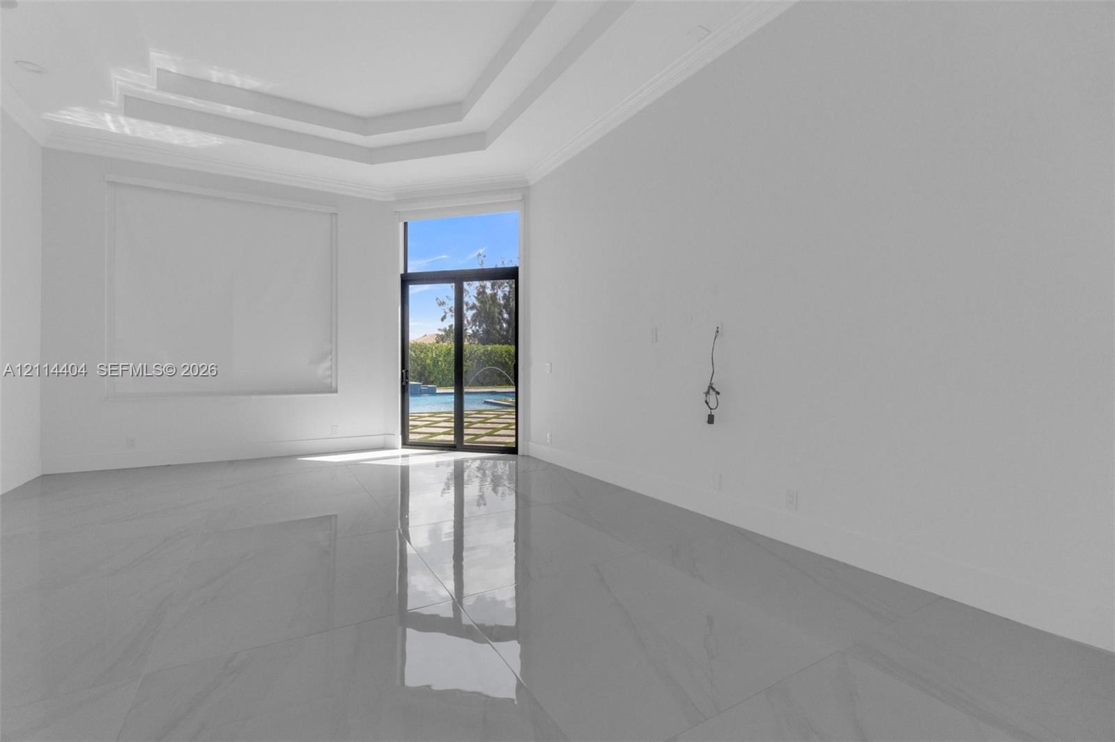 High-ceiling living area featuring tray ceilings, large-format tile flooring, and sliding glass doors